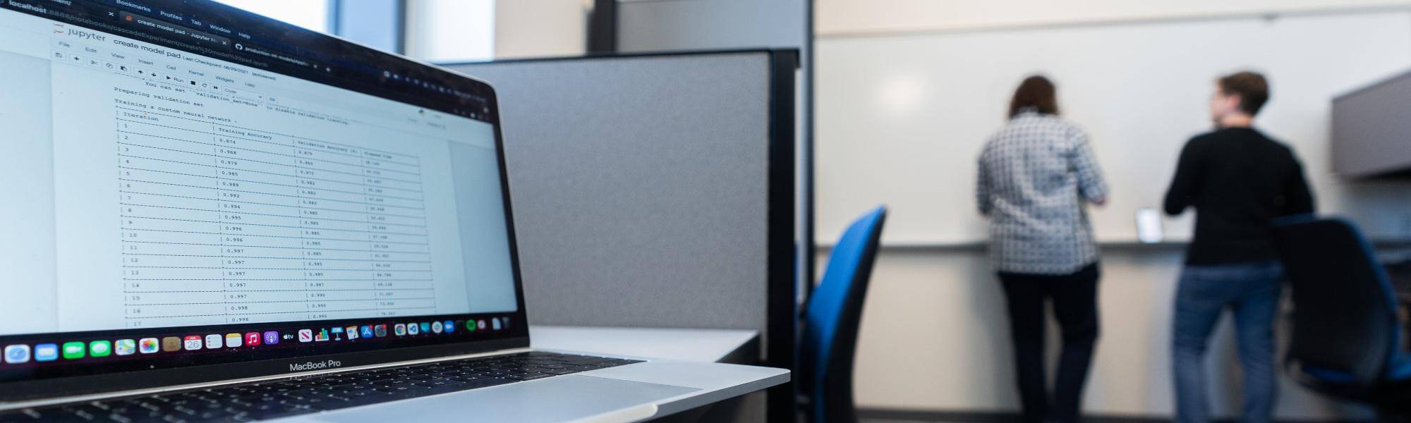classroom with a laptop open and students in the background